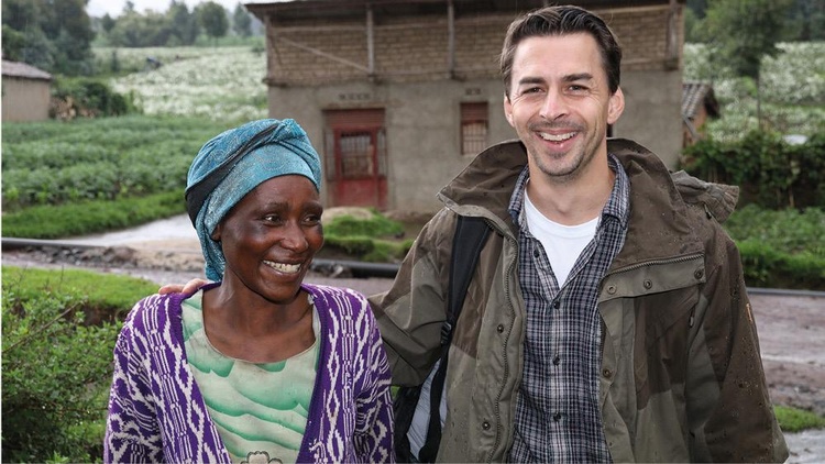 Michael Novoszad (CEO Likano) steht mit Ancille Mukasine vor einem Haus im Dorf