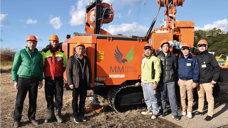 Mitarbeiter stehen bei einer Forstmaschine in Japan