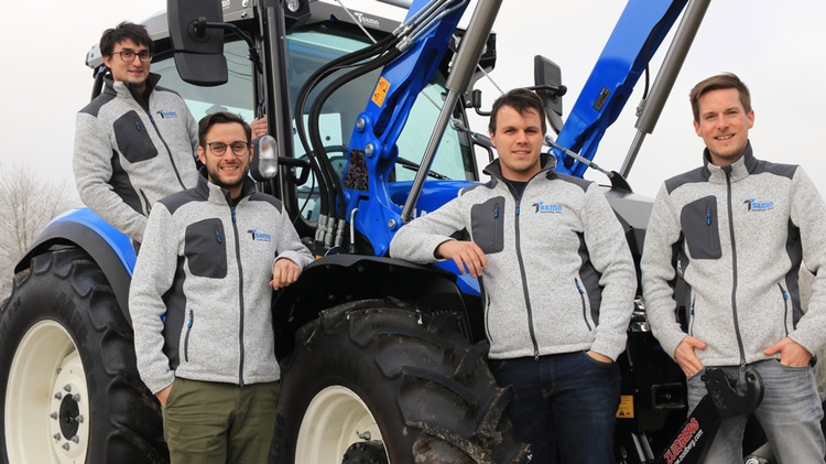 Vier junge Männer vor bzw. auf einem Traktor