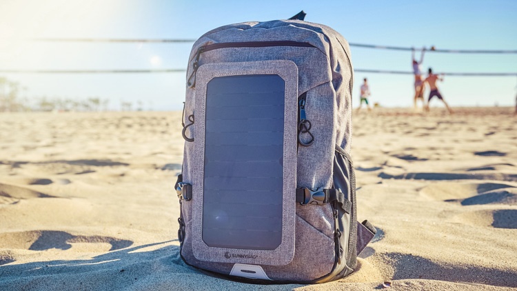 SUNNYBAG Rucksack am Strand. Im Hintergrund spielen Menschen Volleyball.