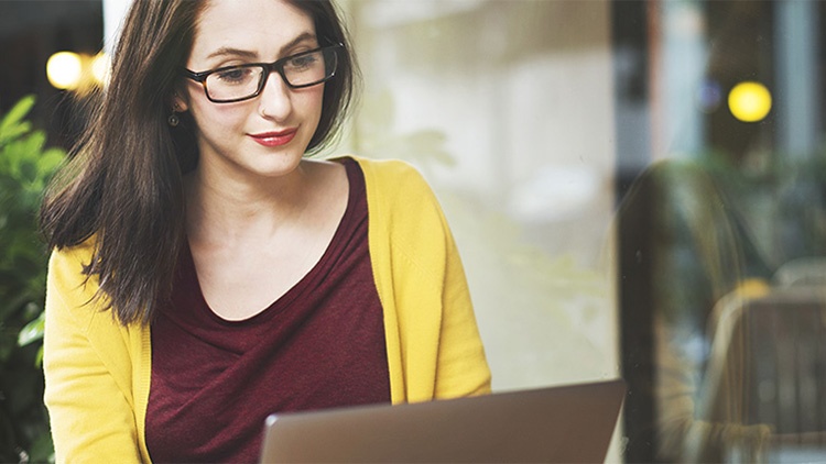 © Shutterstock Eine junge Frau mit Brille blickt auf ihren Notebook-Bildschirm